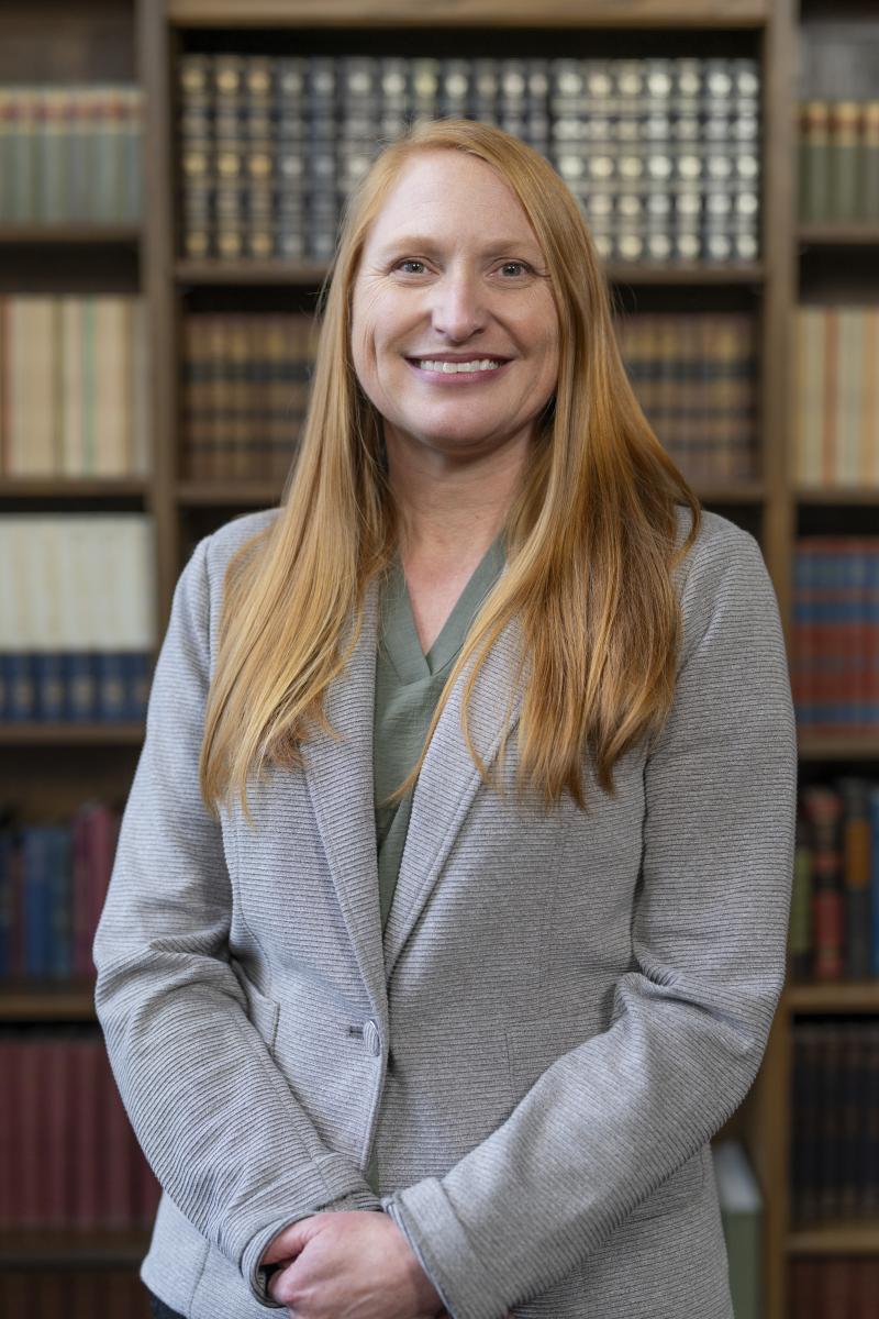 Dr. Thompson smiles in front of a wall of books