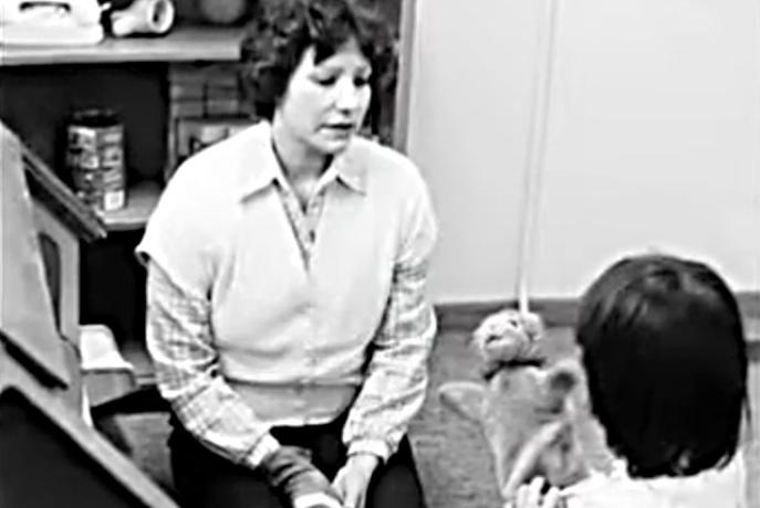 B&W photo of GSPP student and child playing with puppets